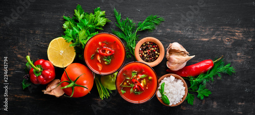 Gazpacho Soup in Glas. Tomato soup with onion, paprika and parsley. Italian cuisine. Top view. On a black background. Free space for text.