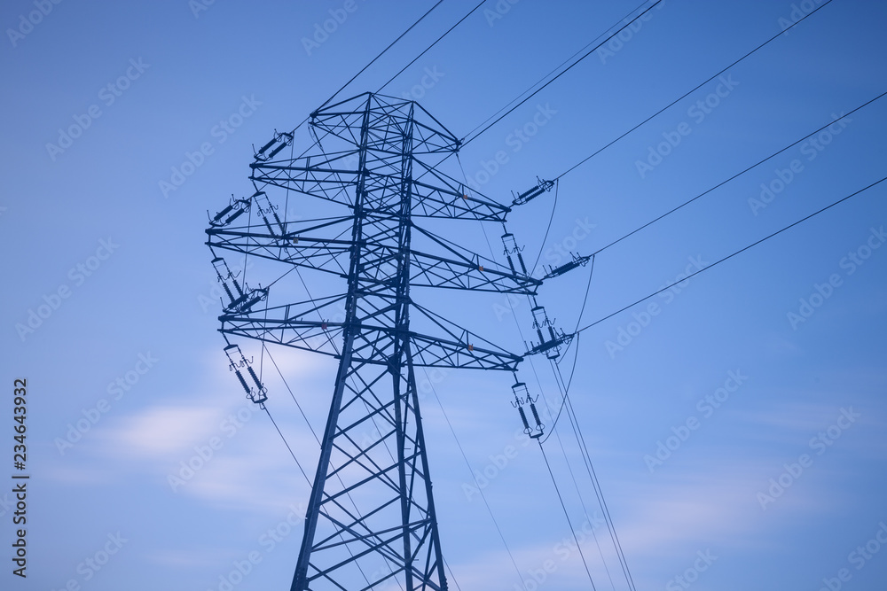 High voltage lines and power pylons over the blue sky.