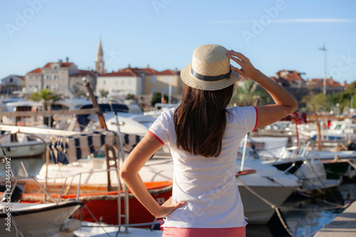Europe summer travel mediterranean destination. Tourist woman on vacation, walking on the marina of old Mediterranean city. Budva, Montenegro