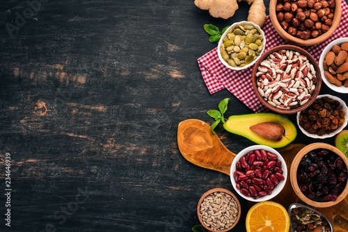 Various superfoods. Dried fruits, nuts, beans, fruits and vegetables. On a black wooden background. Top view. Free copy space.