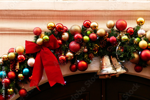 Canvas Print Colorful Christmas decor balls and bell over the door as seasonal decoration
