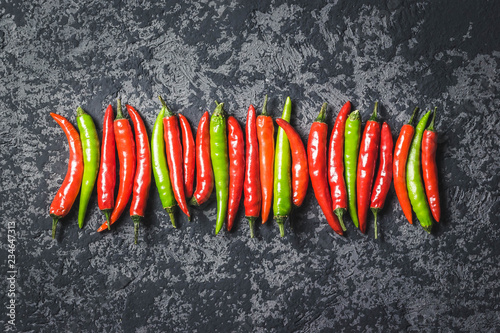 Red, green chili peppers on dark concrete background. Top view, space for text.