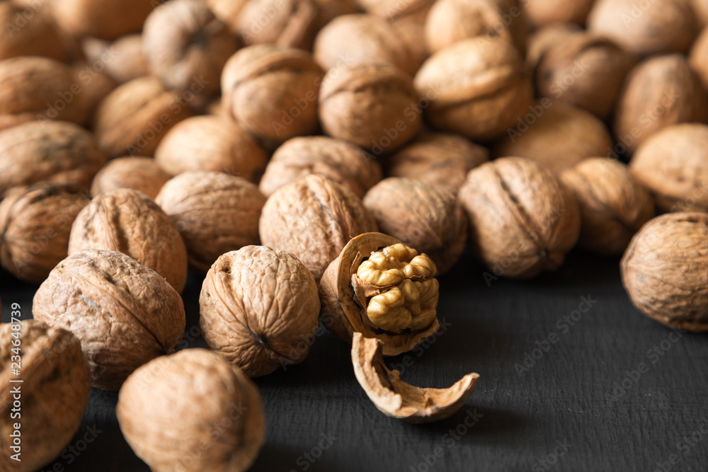 Halved and whole walnuts on black background, side view. Close-up. Selective focus. Halved and whole walnuts on black background, side view. Close-up. Selective focus.