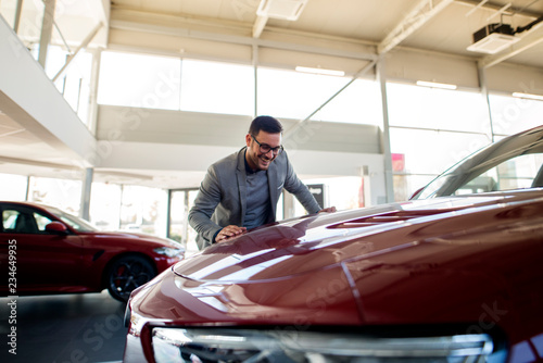 Buyer at car dealership showroom choosing his favorite automobile.