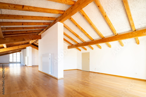 Large empty room with wooden beams and parquet