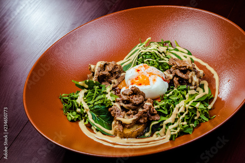 Hot appetizer salad with potatoes, meat, green peas, poached egg photo