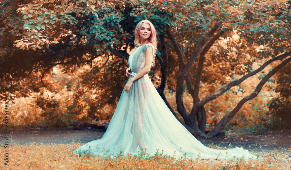 A nice girl is walking in a fairy forest, in a dress, in underwear.  The blonde model is looking back