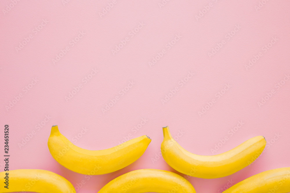 Beautiful, fresh, yellow bananas on pastel pink background. Mockup for different ideas. Empty place for text, quote or logo. Top view.
