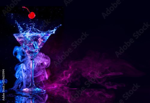 cherry falling into a martini splashing on blue and purple smoky background