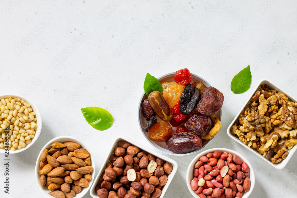 Various Nuts in a ceramic bowl and Dried Fruits on a light stone table. The Concept of a Healthy Dessert. Top view flat lay background. Copy space. Various Nuts in a ceramic bowl and Dried Fruits on a light stone table. The Concept of a Healthy Dessert. Top view flat lay background. Copy space.