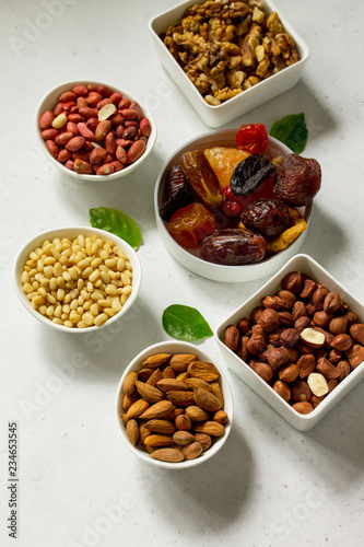 Various Nuts in a ceramic bowl and Dried Fruits on a light stone table. The Concept of a Healthy Dessert. Copy space.