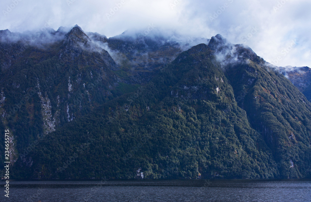 Mountains peaks in clouds on the Lake Manapouri in Fiiordland in New Zealand in the South Island in New Zealand