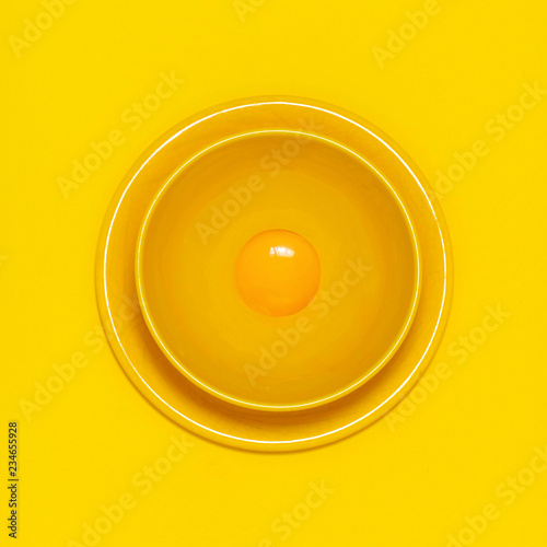 Chicken egg yolk in yellow bowl on yellow background