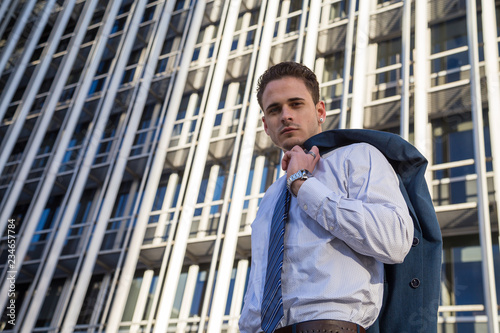 Wallpaper Mural Businessman in classy suit holding his jacket on background of modern office skyscraper. Torontodigital.ca