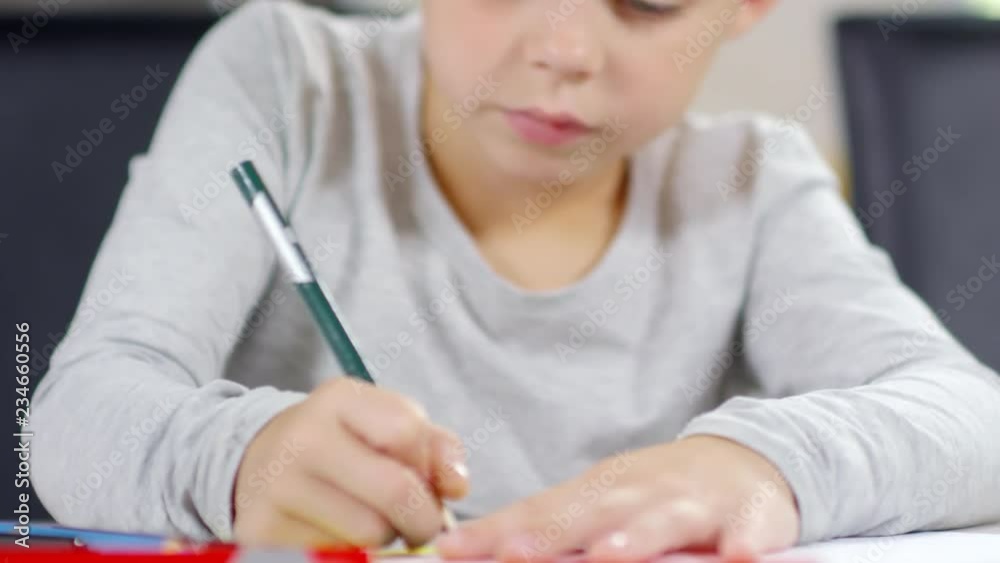 Tilt down shot of talented little boy sitting at table and drawing with colored pencils on paper Tilt down shot of talented little boy sitting at table and drawing with colored pencils on paper