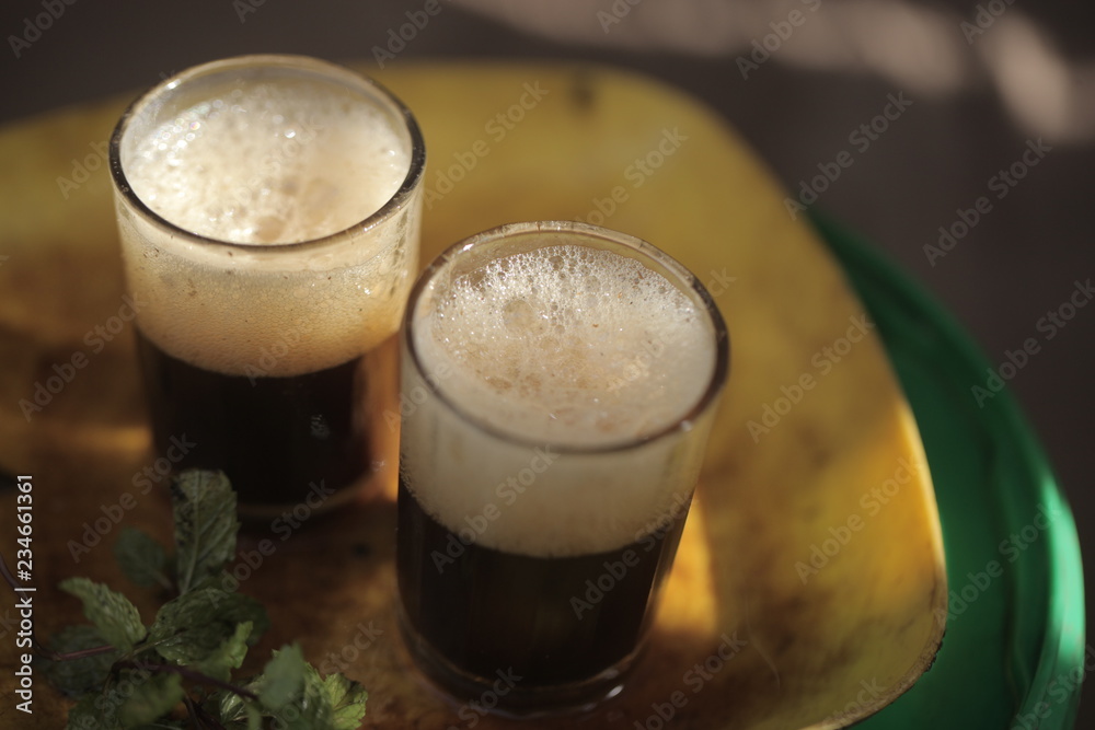 close up of traditional african tea - black strong green attaya in small glasses on a yellow plate, outdoors in the Gambia, Africa close up of traditional african tea - black strong green attaya in small glasses on a yellow plate, outdoors in the Gambia, Africa