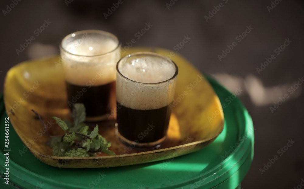 close up of traditional african tea - black strong green attaya in small glasses on a yellow plate, outdoors in the Gambia, Africa close up of traditional african tea - black strong green attaya in small glasses on a yellow plate, outdoors in the Gambia, Africa