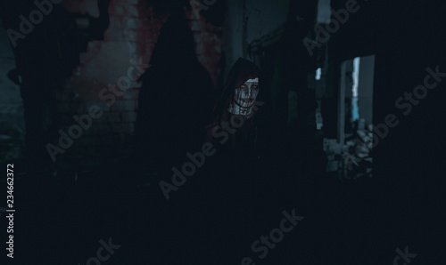 Woman is standing in a darkness dressed an image of a nun possessed by demons.