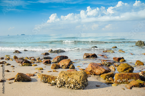 sandy beach with rocks  against ocean blue sea and nice blue sky photo