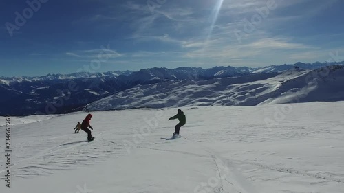 3 snowboarders carve through snow field.    
