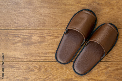 Closeup of Black hotel slippers on wooden ground. Top view. Copy space.