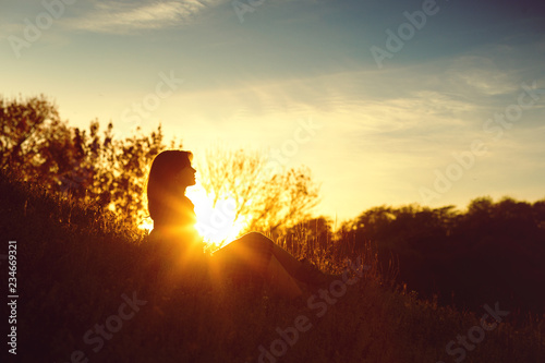 silhouette of a young woman sitting on a hill at sunset in autumn  the concept of human and nature
