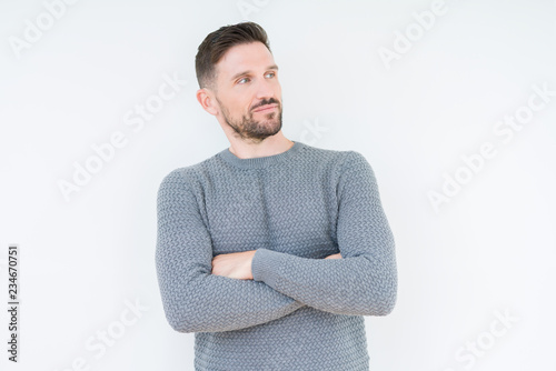 Young handsome man wearing casual sweater over isolated background smiling looking to the side with arms crossed convinced and confident