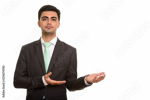 Portrait of young handsome Persian businessman showing something