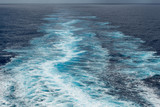 Foam trail in the sea behind the stern of the ship against the horizon