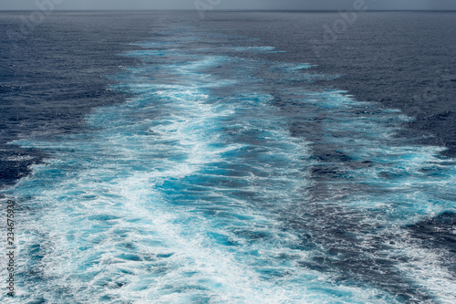 Foam trail in the sea behind the stern of the ship against the horizon © DOF