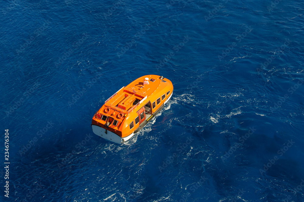 Orange rescue boat on blue sea waves background. Aerial view