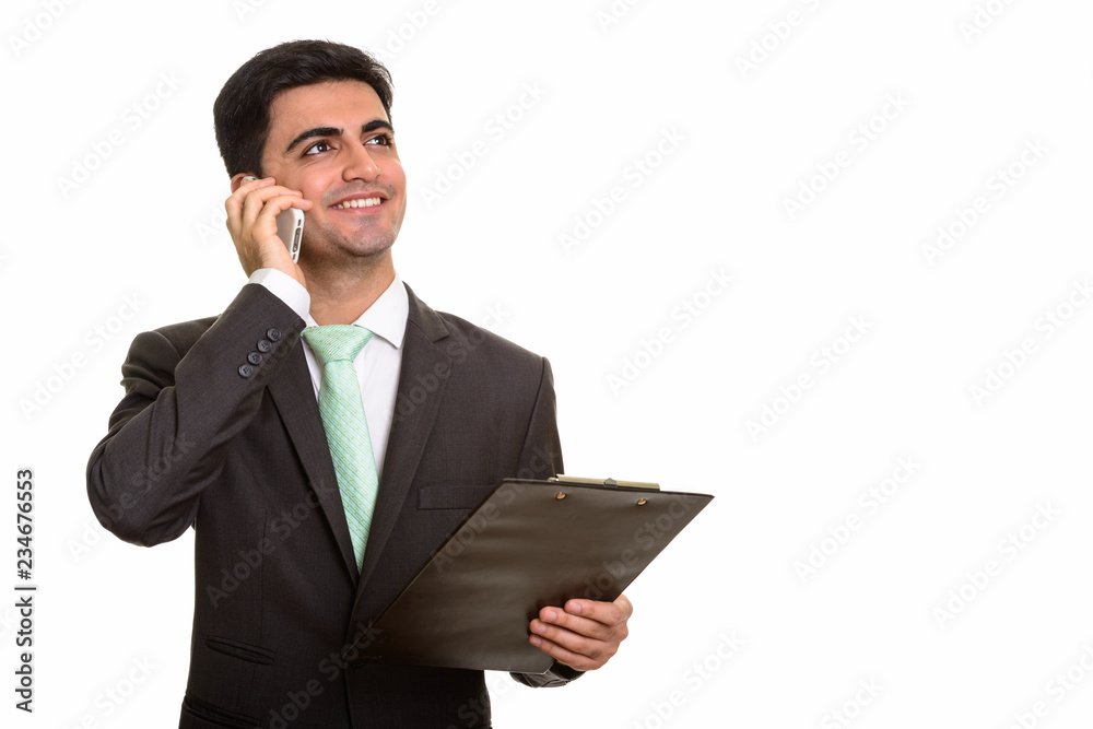 Young happy Persian businessman talking on mobile phone while ho Young happy Persian businessman talking on mobile phone while ho