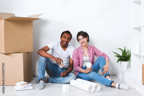 Happy young couple sitting on floor dreaming.