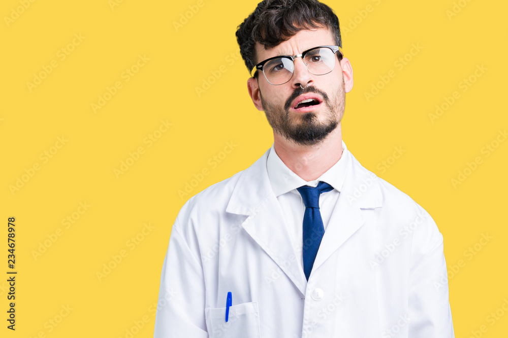 Young professional scientist man wearing white coat over isolated background In shock face, looking skeptical and sarcastic, surprised with open mouth Young professional scientist man wearing white coat over isolated background In shock face, looking skeptical and sarcastic, surprised with open mouth