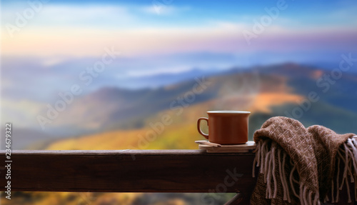 Hot cup of tea or coffee on the wooden railing on the background of the mountains.	
