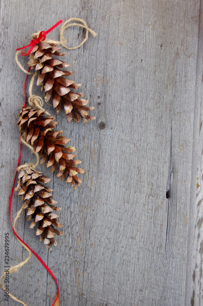 three pinecones with twine and red ribbon on rustic wooden background with copy space three pinecones with twine and red ribbon on rustic wooden background with copy space