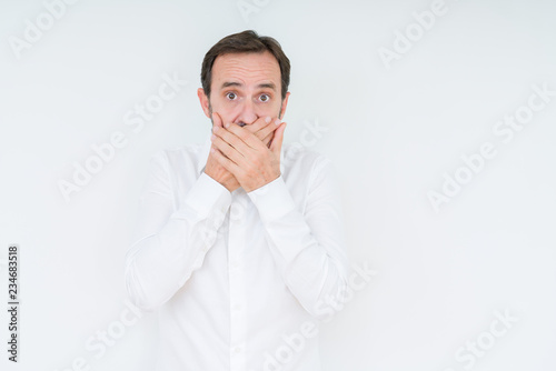 Elegant senior man over isolated background shocked covering mouth with hands for mistake. Secret concept.