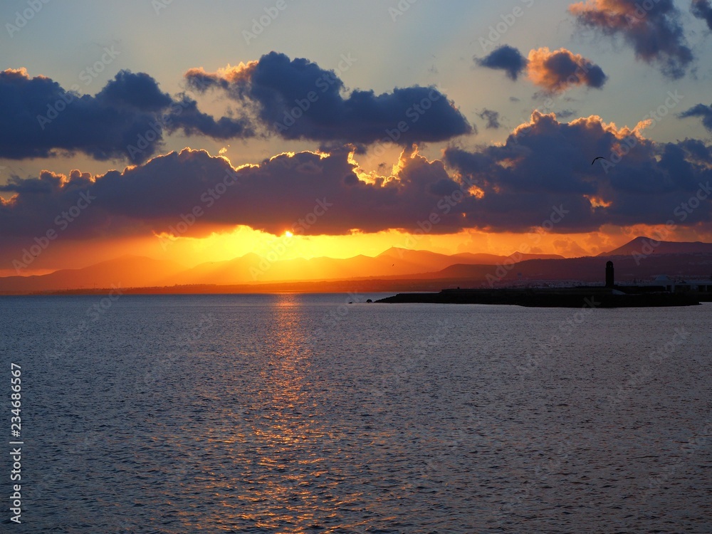 Glowing sunset behind dark clouds over the ocean at Arrecife, Lanzarote, Canary Islands