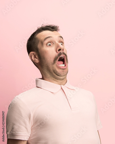 Fotografie, Obraz The surprised and astonished young man screaming with open mouth isolated on pink background