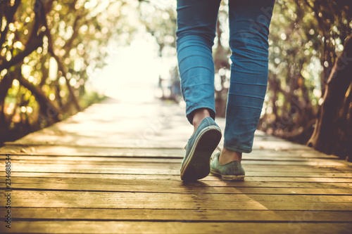 Man is walking on small wood bridge to nature walk way.