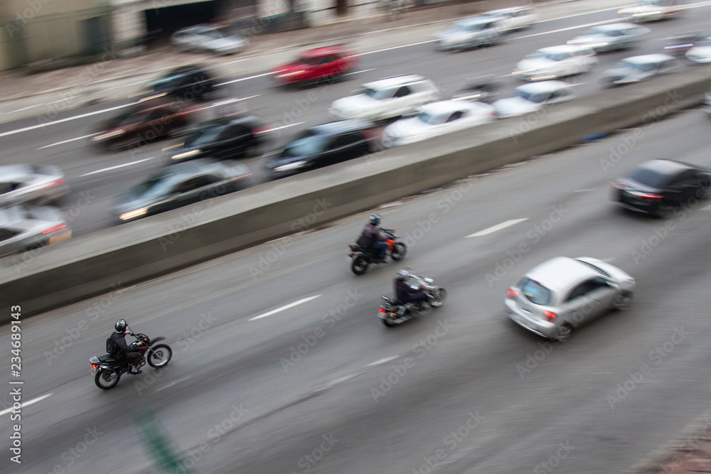 Pan shoot of motorcycles at high speed on a avenue.