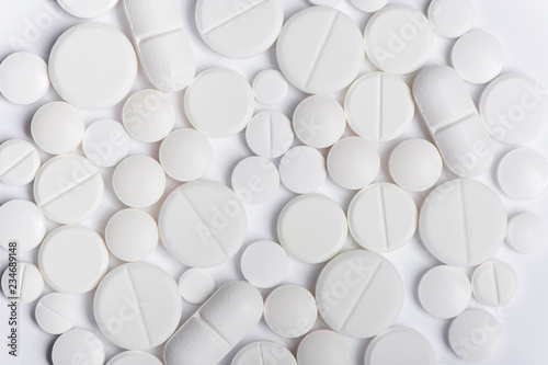 Close up view of heap of white pills on white background,