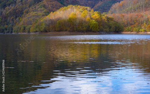 The forest in autumn is reflected in the Endara reservoir, Navarra