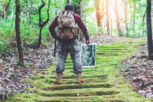 Hiking man with backpack and trekking boots on the bright green moss passage trail in forest