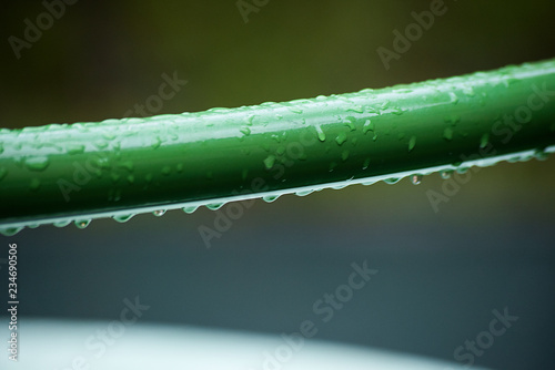 Green metal tube covered with water drops
