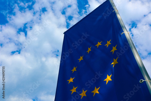 European union flag, blue sky on the background. Blue European union flag with yellow stars in a circle waving on wind. Macro view, close up.