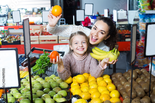 Smiling mother and daughter buying fruits