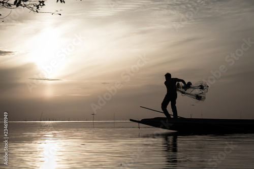 Silhouette of traditional fishermen throwing net fishing at sunrise time, livelihoods of fishermen at Pakpra, Phatthalung in Thailand
