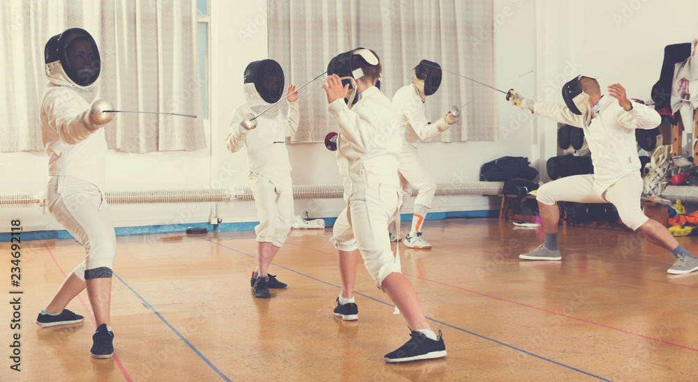 Boys and adults practicing fencing techniques