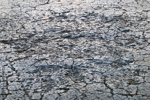 Low angle close up view of cracked and damaged roadway tar asphalt.